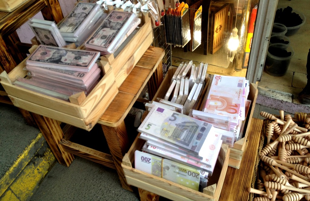 Realistic dollar and euro notes on sale in the market, next to the honey sticks.